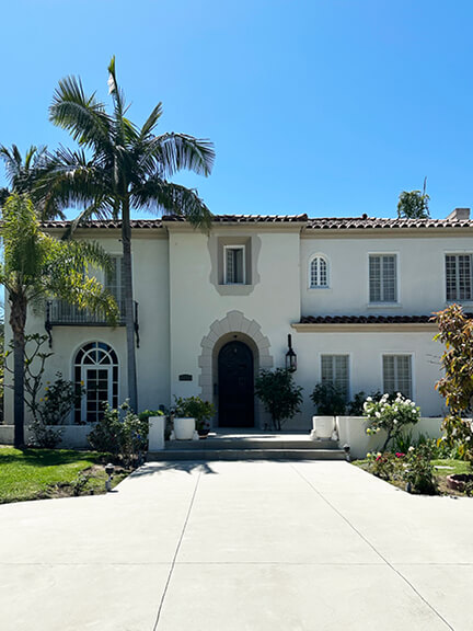A stucco home in Los Angeles with a tile roof, soft grey trim, and a tall palm tree—simple lines and classic curb appeal.