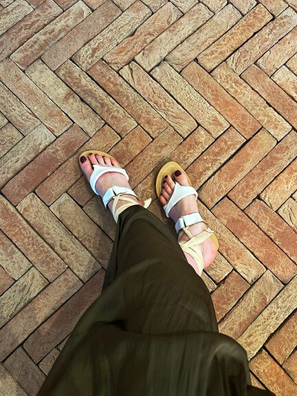 Terracotta herringbone floor tiles paired with Sarah Flint wrap sandals, highlighting material texture and style in a retail environment.