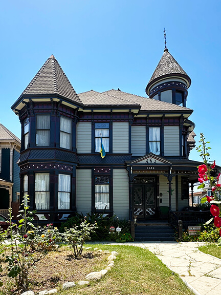A Victorian home in Angelino Heights painted in navy, burgundy, and off-white, with ornate trim and a steep gable roof.