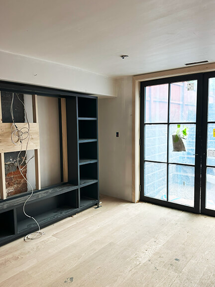 Walk-out basement media room with white oak floors and custom shelving in a historic Boston brownstone