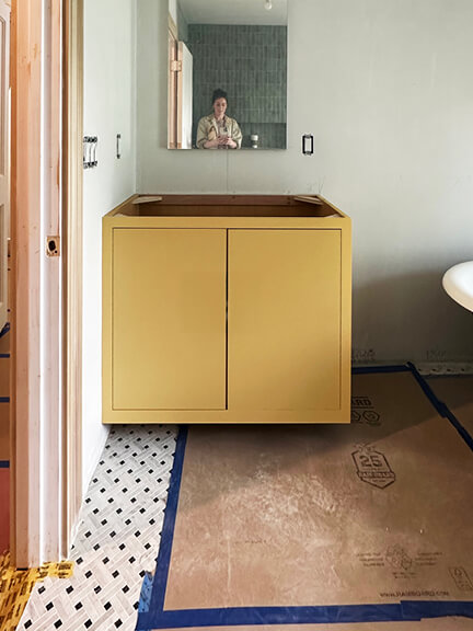 Yellow vanity and basketweave marble tile floor in a classic bathroom of a historic Boston brownstone