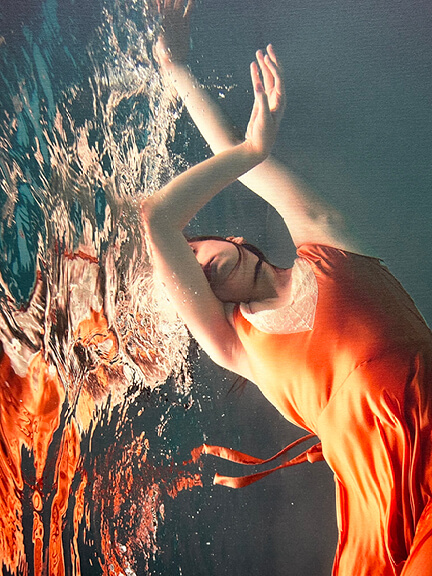 Art in interior design featuring Alyssa Fortin’s underwater photo of a ballet dancer in a bright orange dress, shown at South Shore Art Center
