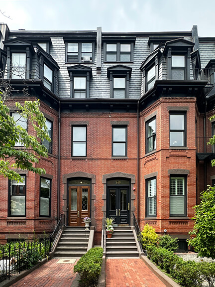 Side-by-side red-brick Victorian rowhouses with bay windows and granite bases—showcasing historic home design in Boston’s Back Bay.