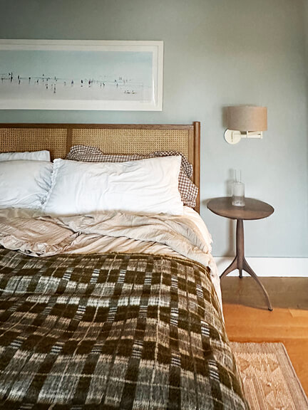 Bedroom with cane bed, surf art, and soft blue walls.