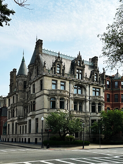 Ornate limestone Boston mansion with arched entry and mansard roof—an iconic historic residence in the heart of Back Bay.