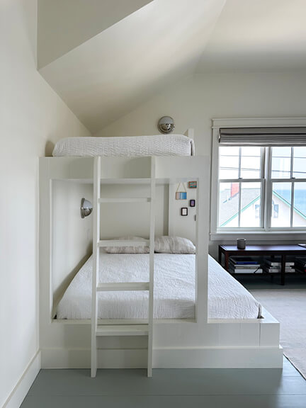 Custom white bunk beds with built-in ladder and coastal detailing.