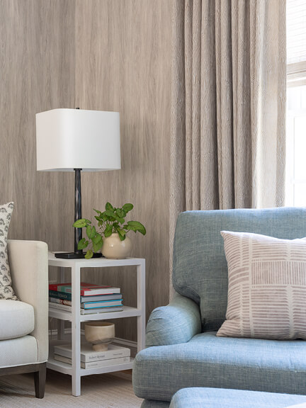 Custom window treatments with drapery panels layered over French faux bois wallpaper in a Hingham family room with a blue and neutral palette