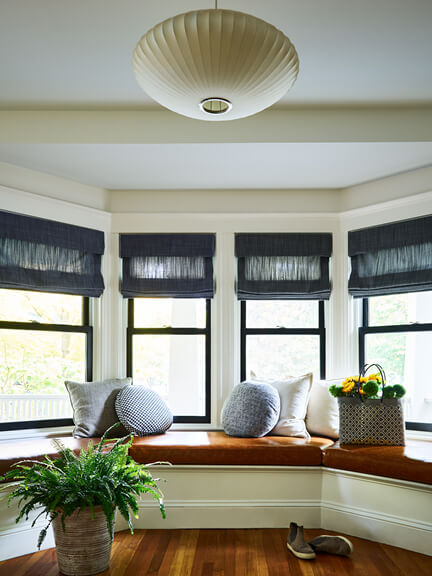 Charcoal linen Roman shades on black windows add privacy and polish to the formal foyer of a historic Brookline home
