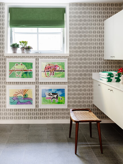 Custom window treatments in a Hingham kids’ bath with green linen Roman shades, coordinating with geometric wallpaper and children’s art