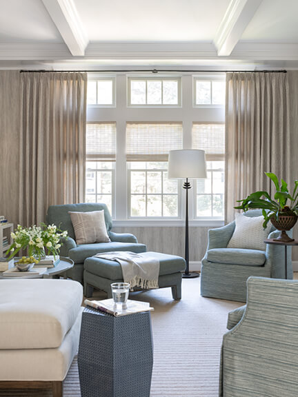 Woven wood shades and Lee Jofa drapery frame French wallpaper in a coastal Hingham family room with soft blues and natural tones