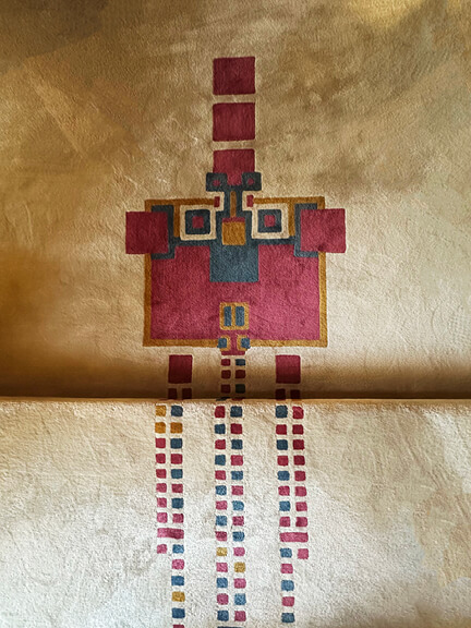Geometric area rug in maroon, gold, and blue at Hollyhock House, seen on a postmodern architecture Los Angeles tour of Mayan Revival design