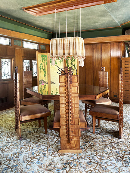 Custom dining room with green ceiling, natural wood lighting, built-in cabinets, and vintage rug at historic LA home by Frank Lloyd Wright