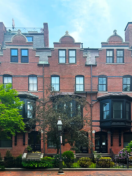 Red-brick Victorian townhouse in Boston’s Back Bay with bay windows, gabled roofline, and classical trim—historic home design in Boston.