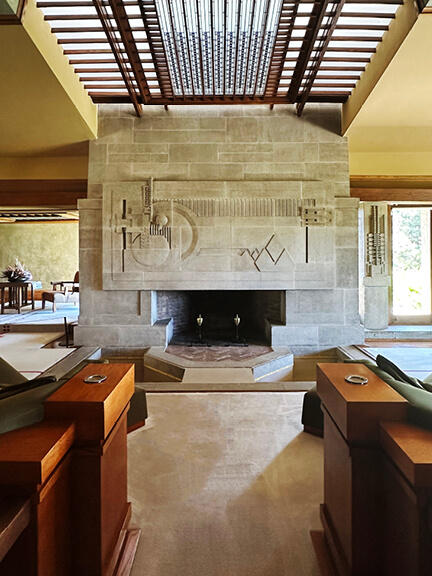 Stone fireplace with trellis ceiling, water feature, and custom furniture at Hollyhock House in Los Angeles