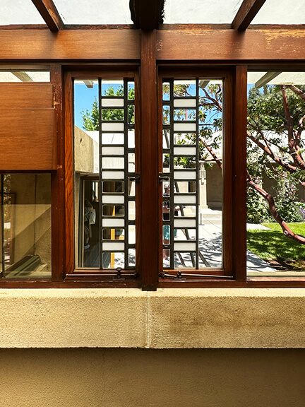 Custom geometric Frank Lloyd Wright windows in corridor leading to courtyard