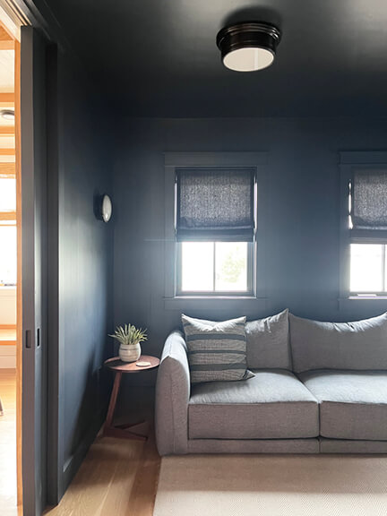 Navy blue media room with roman shades and a denim-toned sectional.