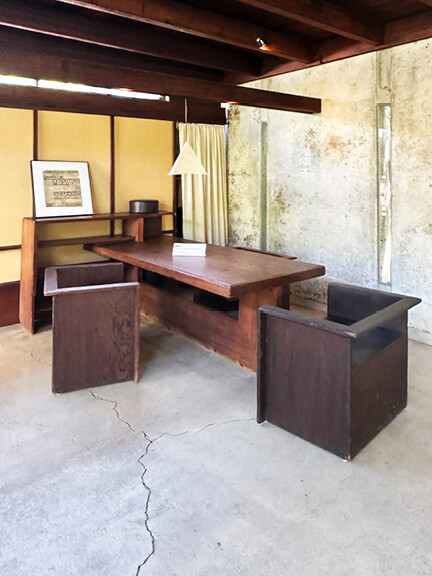 Dark wood furniture, concrete walls, and slot windows define Schindler House interior