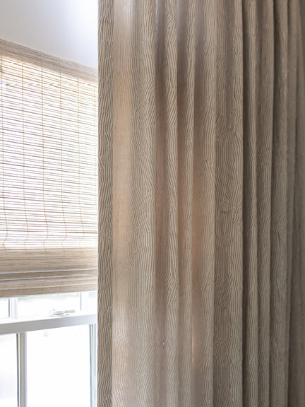 Custom window treatments with Kelly Wearstler drapery and woven wood Roman shades in a South Shore family room