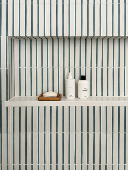 Striped wall tile in a bright attic bathroom with coastal details.
