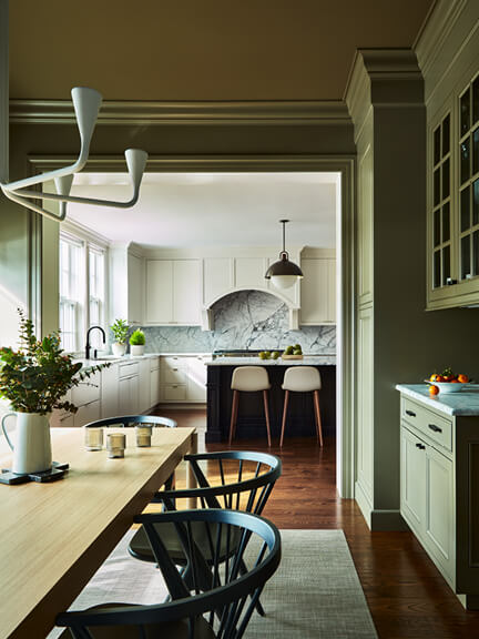 Boston kitchen designer transforms a taupe dining room with modern furniture, view to white kitchen with black island and Allied Maker lighting