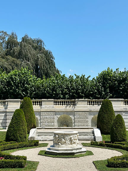 Classic French garden with marble and stone walls at the sunken garden, featuring a central marble fountain at the Newport Rhode Island estate.