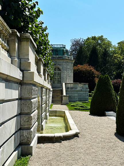 Sunken garden with stone walls and pavilions inspired by a classic French garden, featuring a water fountain at the Newport Rhode Island mansion.