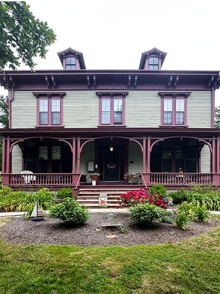 Green and maroon Bullock House with classic New England porch details in Bristol, Rhode Island