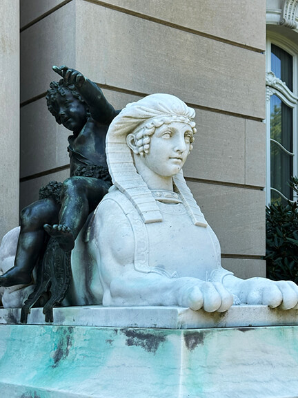 French chateau inspired entry with marble sphinx statue and bronze figure at the front of the historic Newport mansion The Elms.