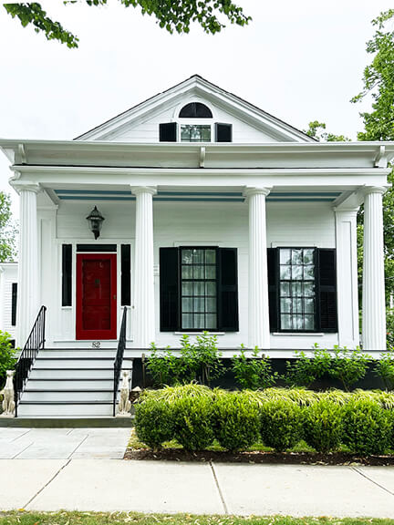 White Colonial Revival home with fluted columns and red door, photographed in historic Bristol, Rhode Island