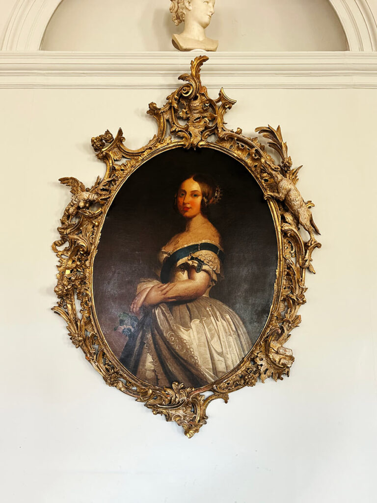 Antique portrait with oval gilded frame in an English manor interior design setting.