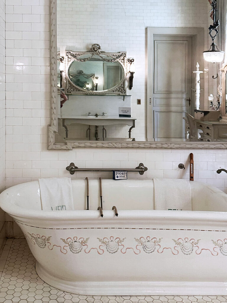 Historic bathroom design at The Elms in Newport with a painted bathtub, marble floor, and classic early 1900s detailing.