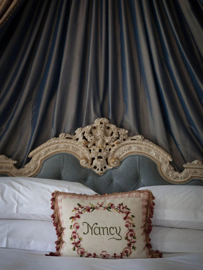 Bed canopy with a vintage pillow in an English manor interior design bedroom at Cliveden House.