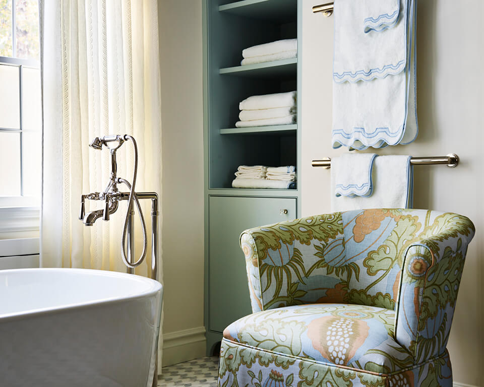 IFDA New England Awards winning bathroom with blue cabinets, polished nickel fixtures, marble floor, and a Christopher Farr slipper chair
