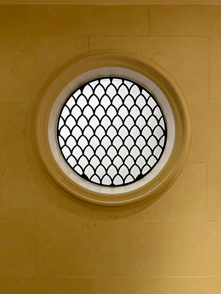 London restaurant design features a circular window with iron detailing on a stone wall, highlighting classic British interior architecture.