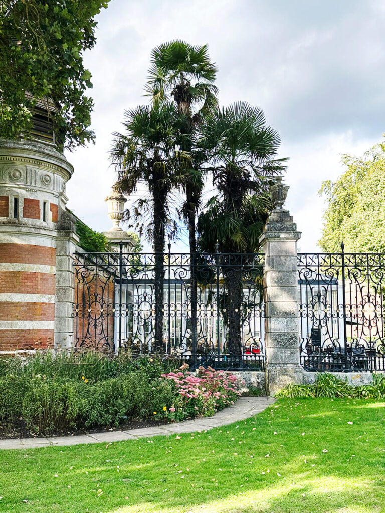 Historic English Estate Design seen in the front garden walls of Cliveden House, with stone pedestals, urns, and manicured hedges.