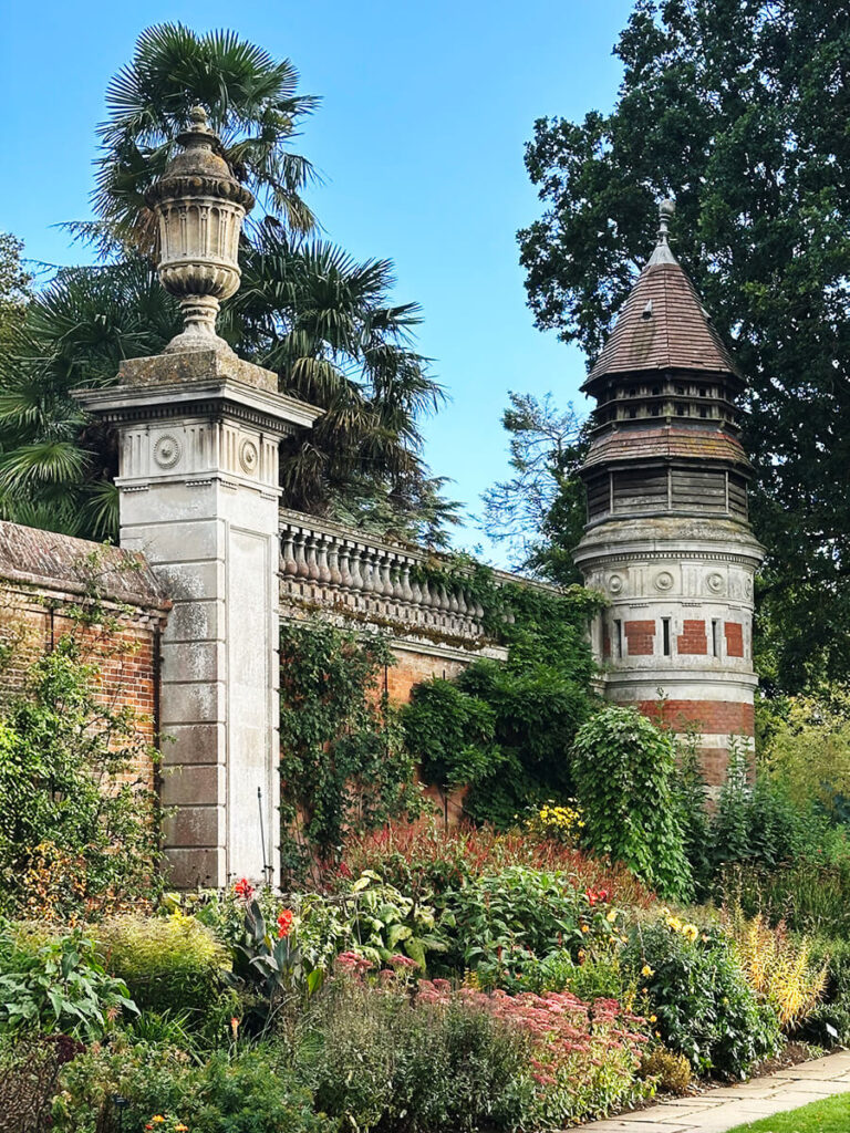 Front gates of Cliveden House with ornate ironwork, stone pillars, and a view toward the grand approach of the historic English estate.