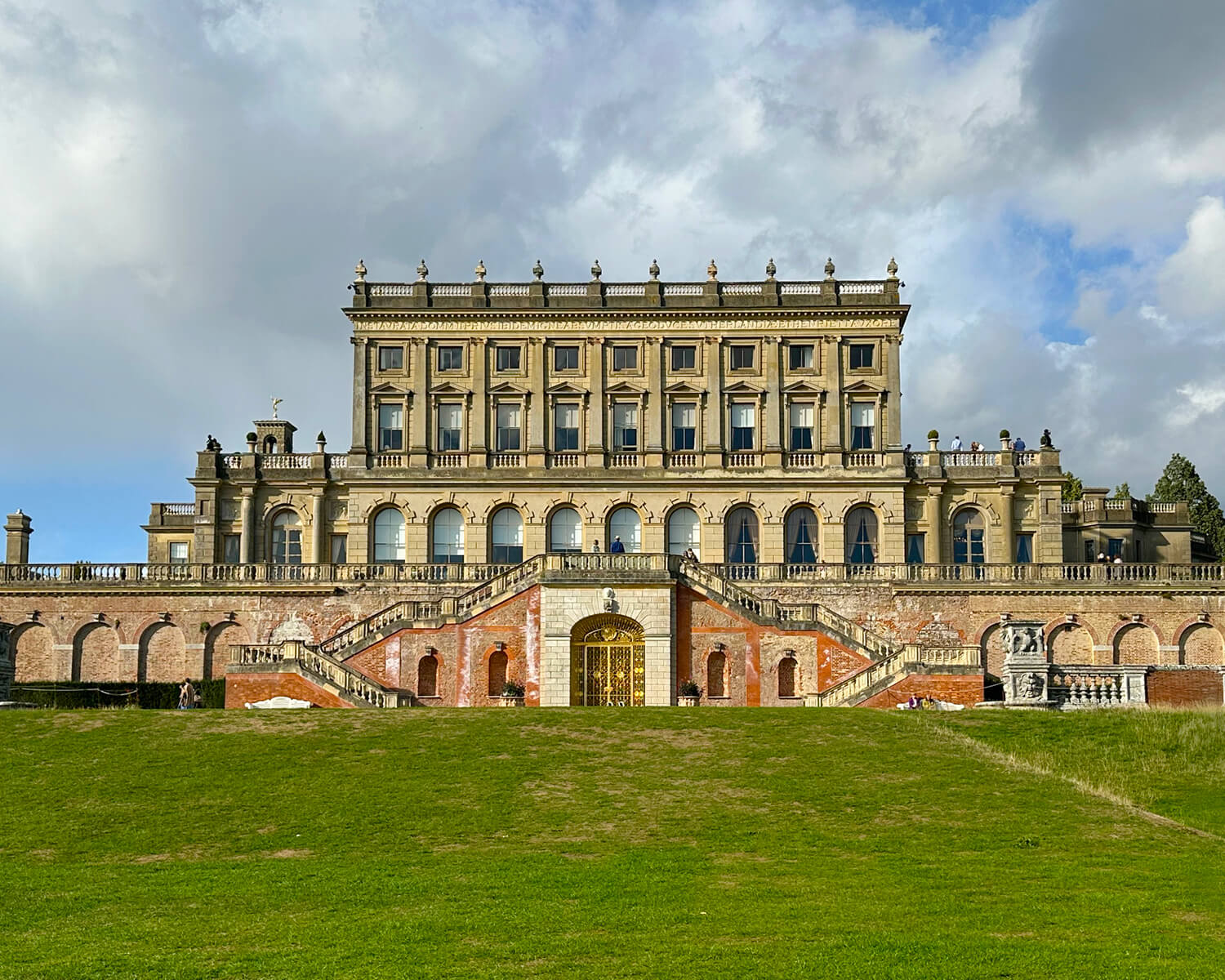 Historic English Estate Design seen in the rear exterior of Cliveden House, featuring stone terraces, arched windows, and formal gardens.