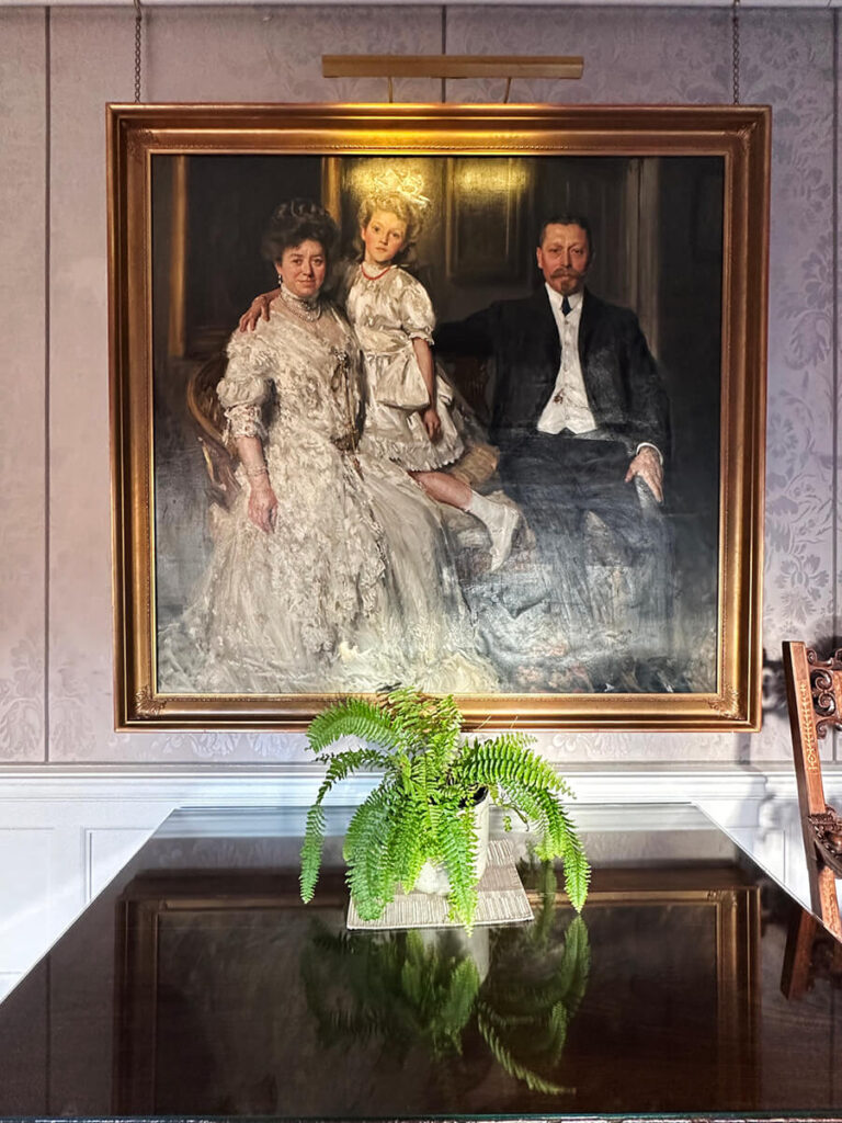 Damask wallpaper and portrait at a historic English home, reflecting timeless English manor interior design.