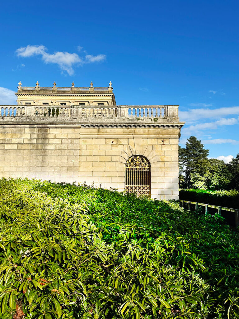 Architectural detail of an English manor estate showing limestone columns, carved cornices, and traditional window proportions.