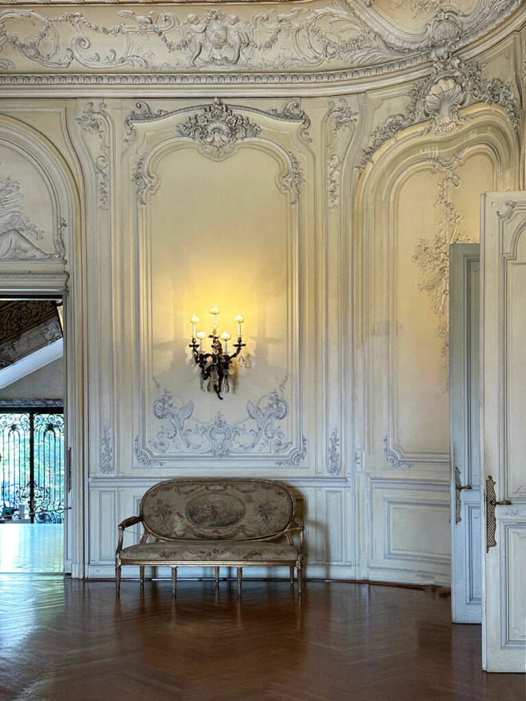 French chateau–inspired ballroom at The Elms in Newport with ornate paneling, crystal chandeliers, and grand architectural detailing.