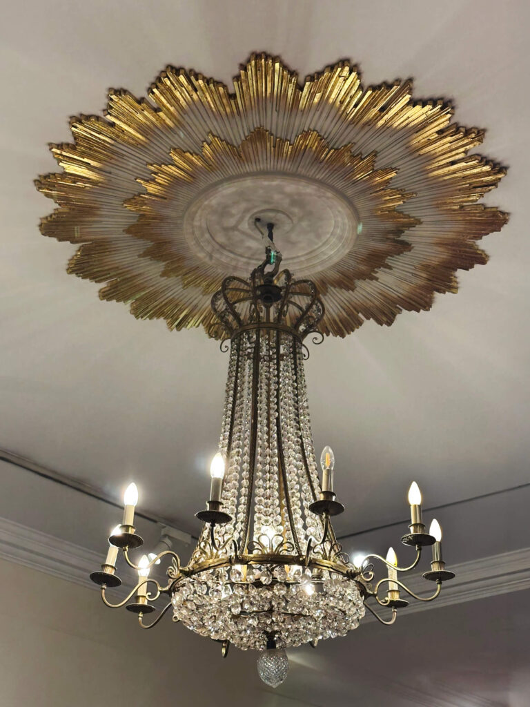 Historic Fortnum & Mason London interior featuring grand light fixture and ceiling medallion, highlighted in Eat Sleep Shop London.