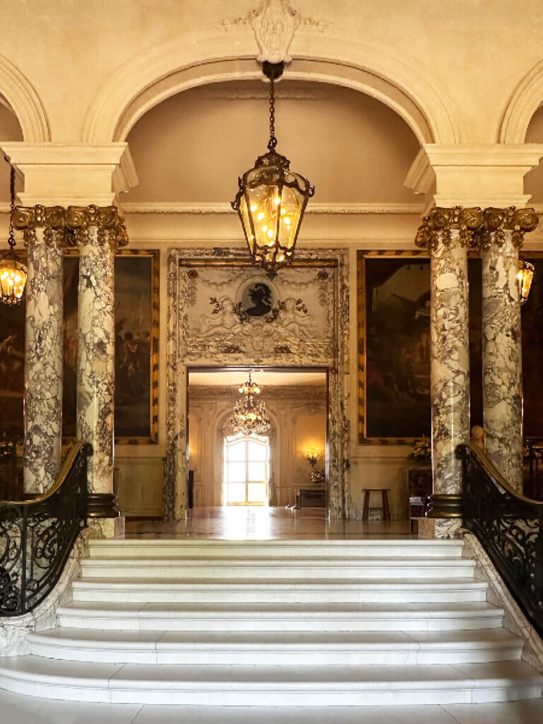 Grand entry at The Elms with marble columns and limestone walls, a dramatic feature of Gilded Age Interior Design.