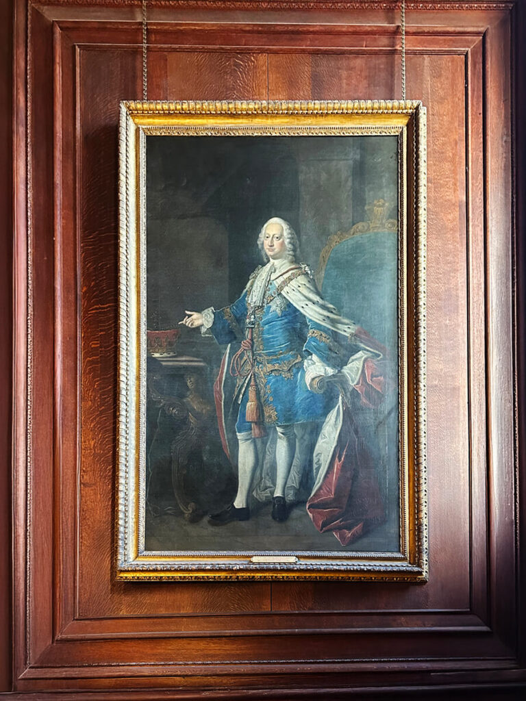 Aristocrat portrait framed by oak paneling on a grand staircase, reflecting English manor interior design.