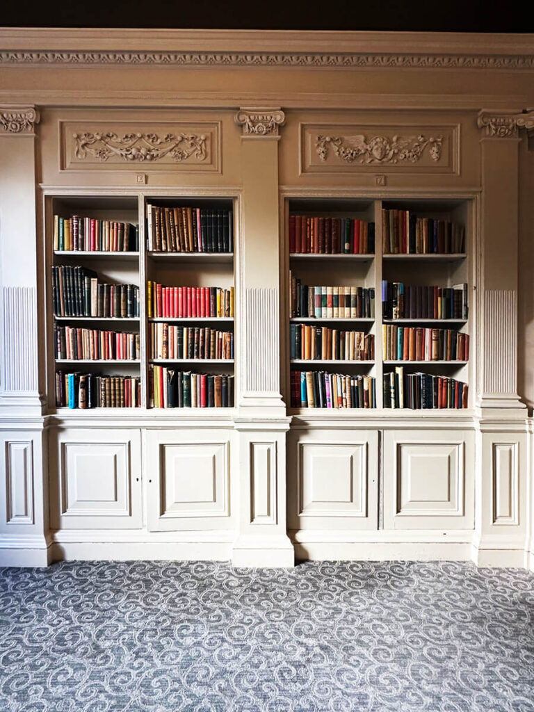 Historic library at Cliveden House featuring carved millwork and proportioned shelves in English manor interior design.