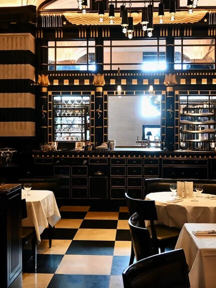 Black and white checkered floors and striped walls at The Wolseley in London create a classic dining interior with bold architectural design.