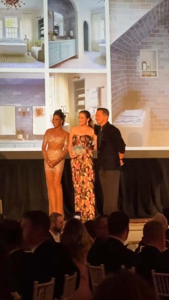 IFDA New England Awards winner Sarah Scales accepts her award on stage with Taniya Nayak and Ricardo Rodriguez at the Boston event
