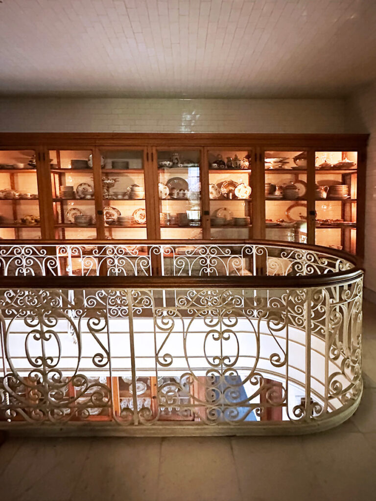 Iron railing and custom cabinets in the two-story kitchen at The Elms in Newport, a lasting symbol of Gilded Age Interior Design.