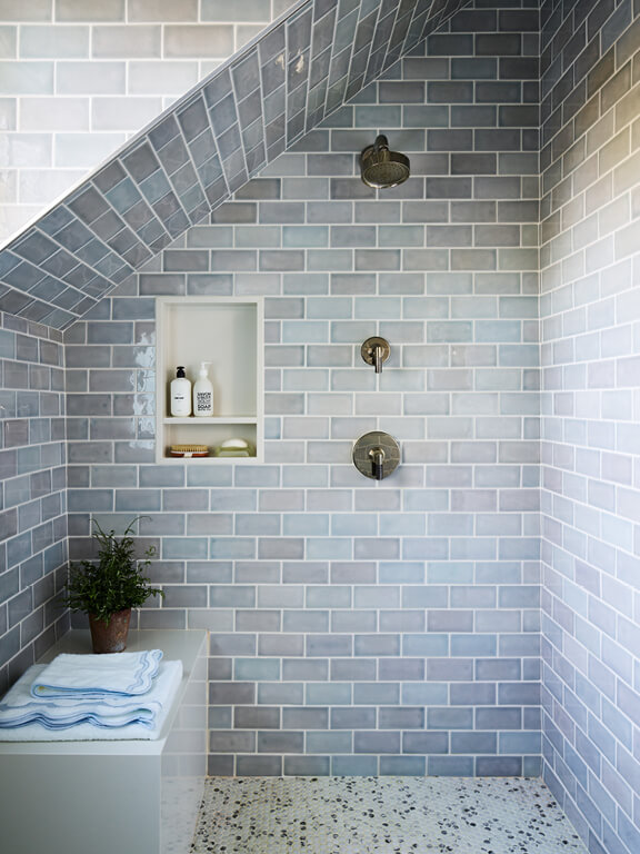 IFDA New England Awards project featuring a steam shower with light blue wall tile, white bench, polished nickel Kallista fixtures, and built-in shower niche