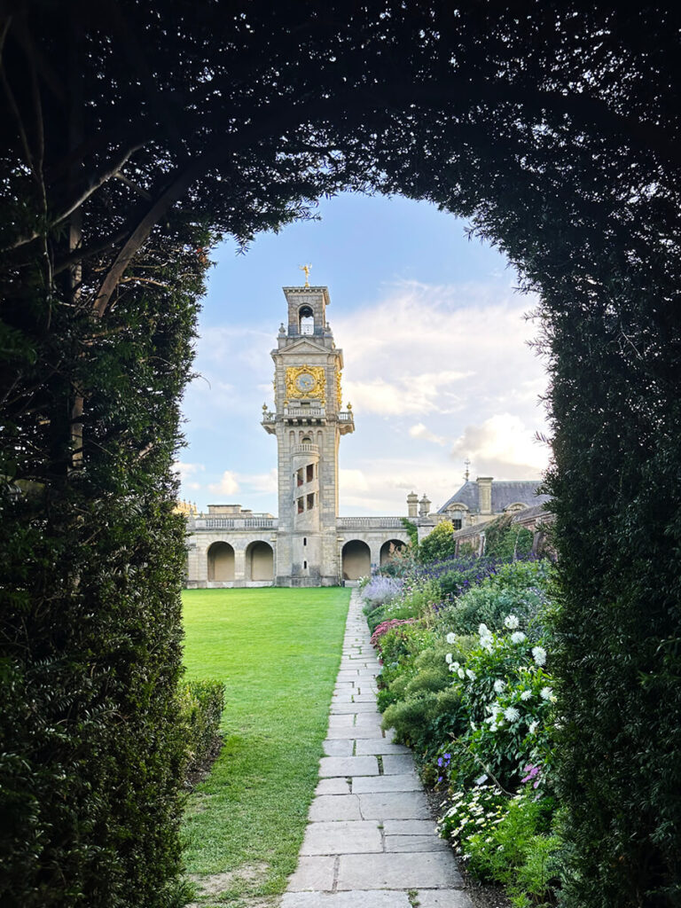 Historic English Estate Design featuring manicured hedges leading toward the stone tower at Cliveden House in the English countryside.