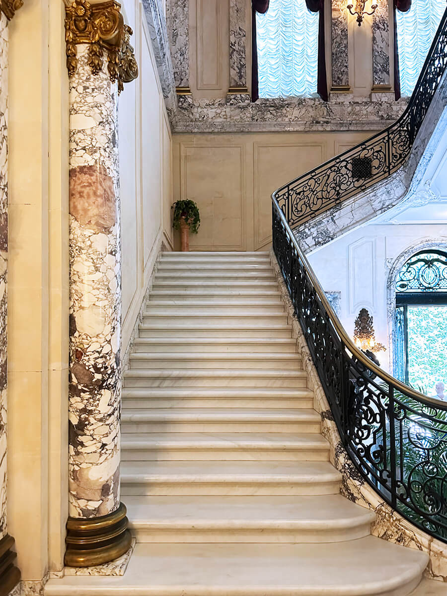 Marble stairs with columns and iron railings at The Elms in Newport, a historic mansion showcasing refined New England craftsmanship.